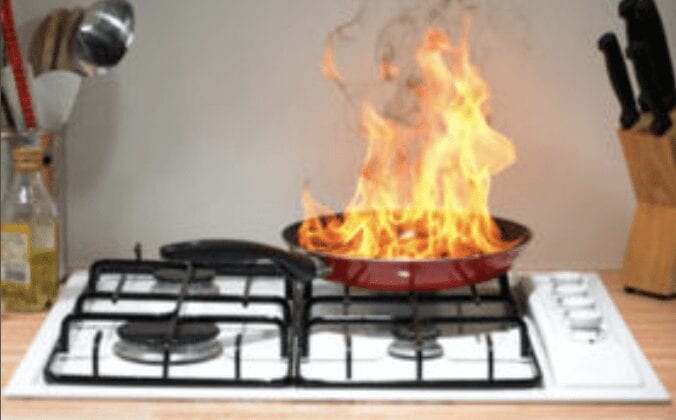 a small fire coming from a cooking pan on a stove top in a kitchen